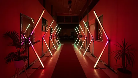 Túnel LED Pixel con luces cálidas y magenta, visto de frente sobre la alfombra roja
