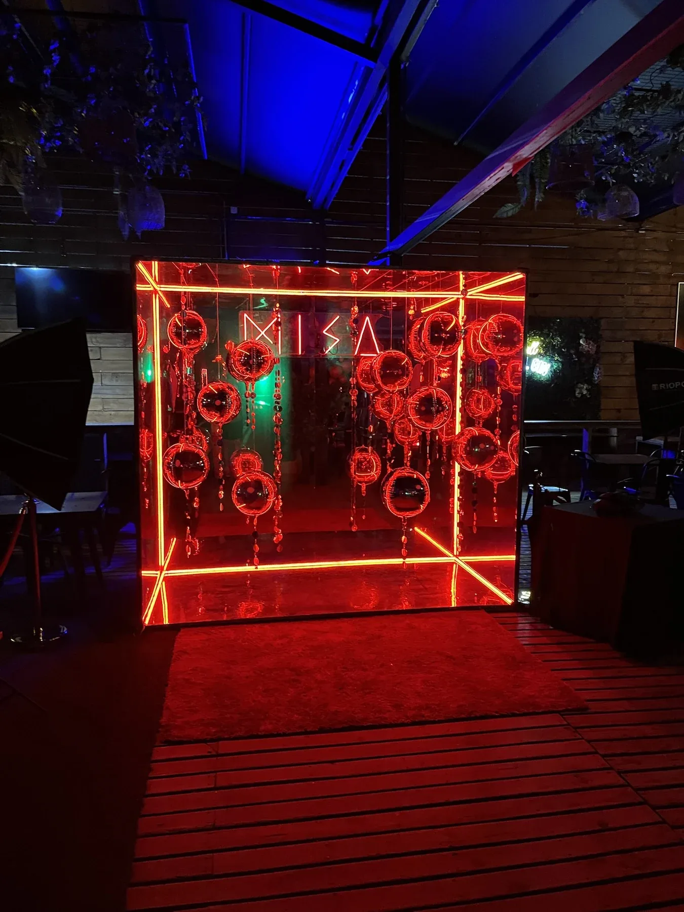 Cabina espejada con iluminación roja sobre una terraza