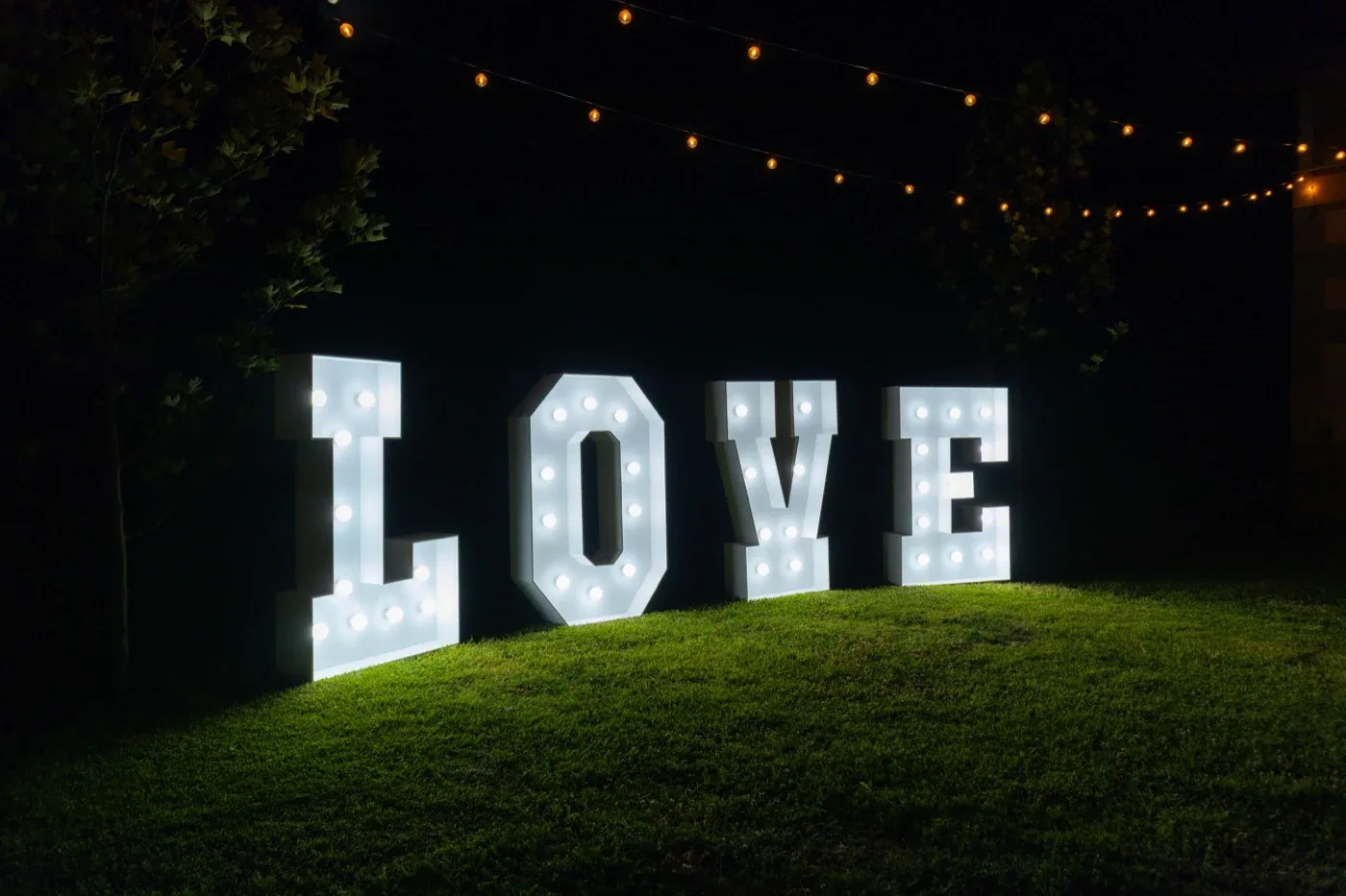 Letras LOVE iluminadas en un jardín de noche